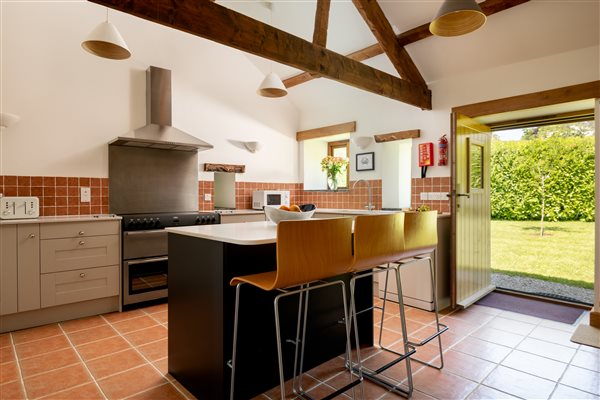 Corn Barn kitchen with island and stools with door open to garden